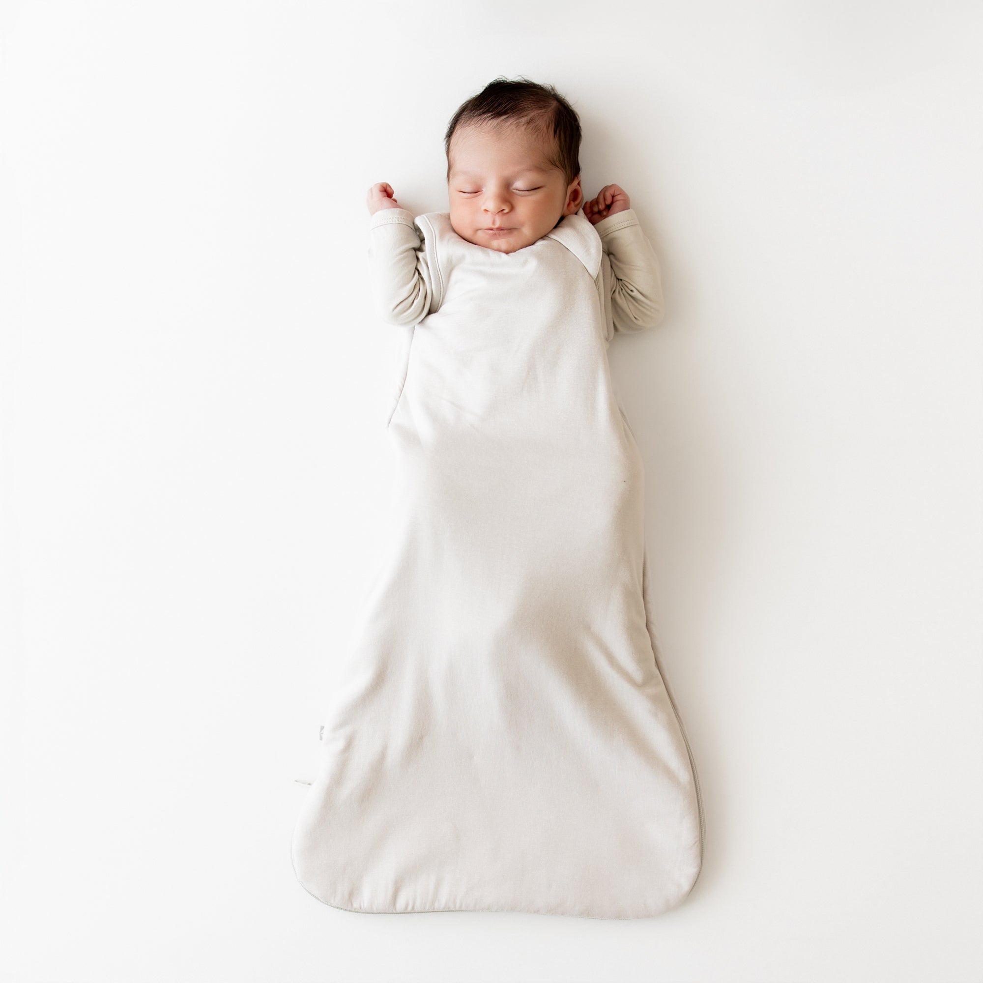 Baby resting in a soft oat-colored bamboo sleep bag — a newborn essential